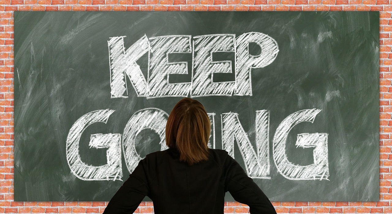 A green chalkboard with the text Keep Going in white chalk